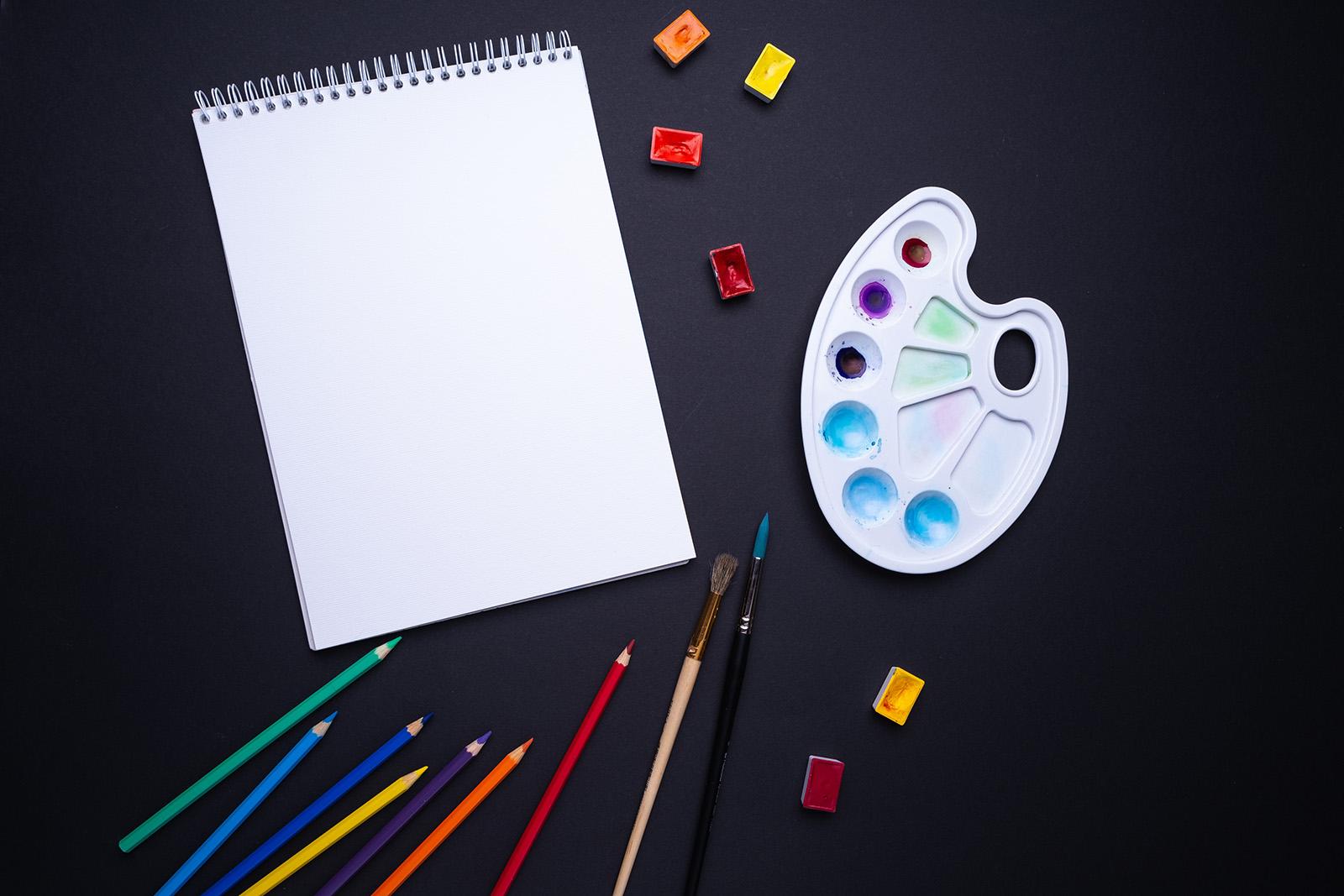 Sketch pad with color pencils and paint brushes - https://unsplash.com/@frostroomhead